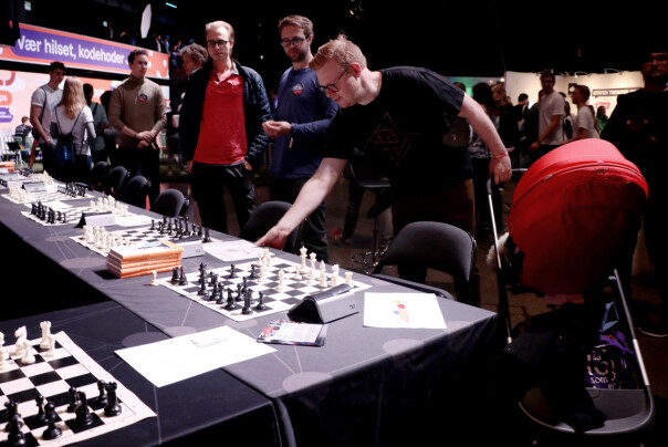 Sopra Steria sin stand på JavaZone 2019. De satsa alle penga på at utviklere liker sjakk. Jørgen pirker litt borti bordet og later som han vet hva han driver med. 📸: Ole Petter Baugerød Stokke