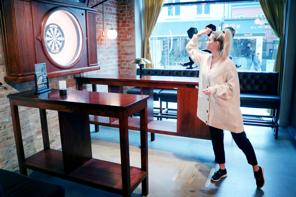 Salgs- og booking-ansvarlig Lovisa Hillberg på Oche tar seg et slag dart. Strekene du ser på gulvet foran beina hennes er opphavet til navnet; for ja, de heter oche, eller kastelinje. 📸: Ole Petter Baugerød Stokke
