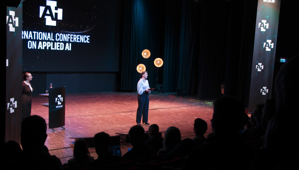 Nesten 400 mennesker hadde funnet veien til Brygga Kultursal i Halden for å følge den femte årlige AI+-konferansen. Konferansier Ruth Astrid Sæter på bildet, med Leonora Onarheim Bergsjø i bakgrunnen. 📸: Kurt Lekanger