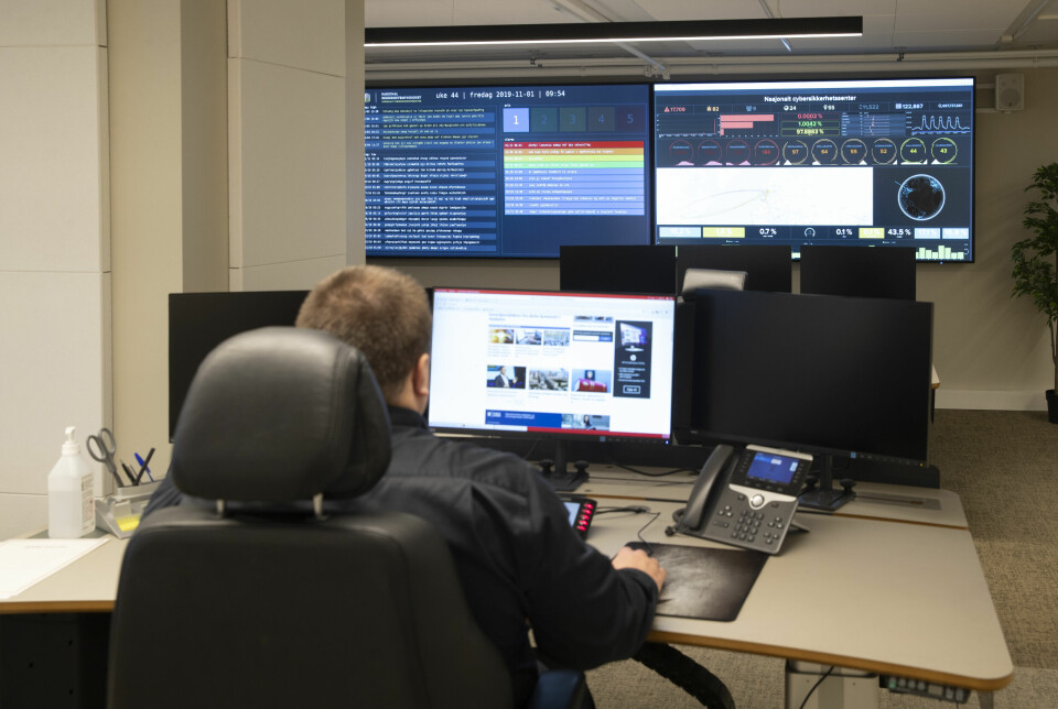 NSM kom onsdag morgen med et nytt rammeverk for håndtering av digitale angrep. Der er rollene tydeliggjort, blant anna hva NCSC (bildet) skal kunne bidra med. Bildet er et interiørbilder av operasjonssenteret under åpningen av NSMs Nasjonalt cybersikkerhetssenter. En mann sitter ved en pult, med tre skjermer på pulten. I bakgrunnen er to store veggmonterte skjermer.