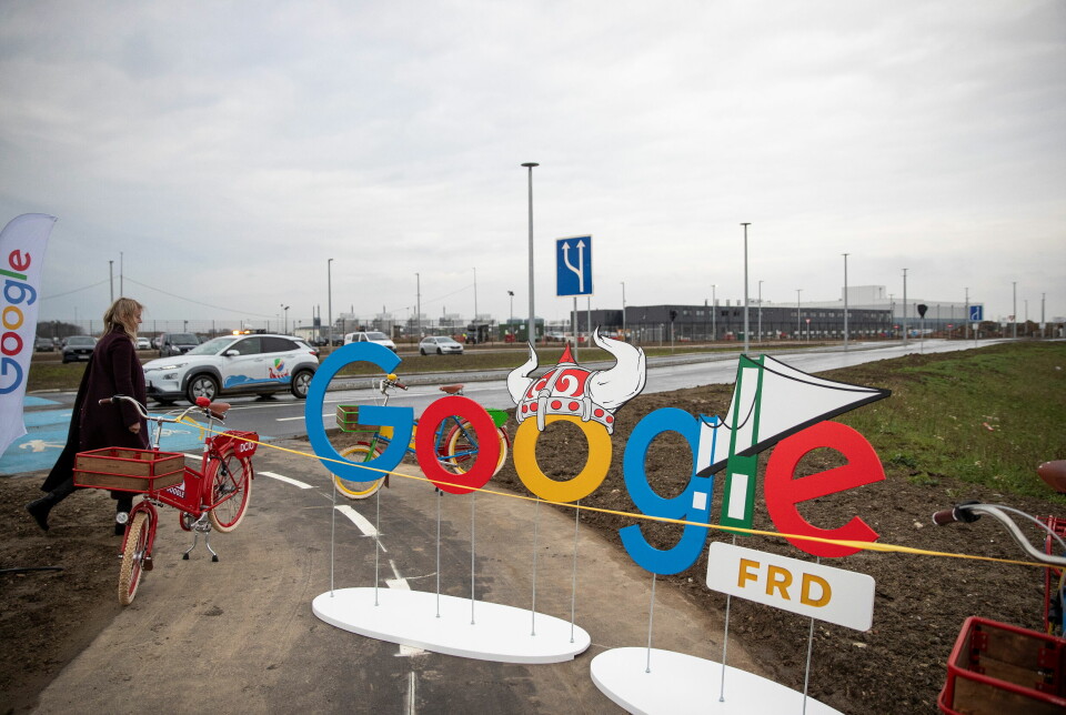 Googles datasentre, som dette i Danmark, har til sammen økt strømforbruket med 27 prosent fra 2023 til 2024. Bildet er av en kvinne med , som passerer et Google-skilt-festet i en rød sykkel.