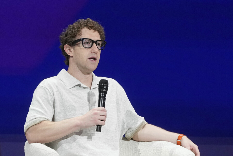 Mark Zuckerberg er saksøkt av flere investorer. De krever at styremedlemmer må ta ansvar for bota Meta fikk i kjølvannet av Cambridge Analytica-skandalen. Bildet er av en hvit mann i hvit piquetrøye som sitter i en hvit stol, foran en blå vegg. Han holder en mikrofon og har på briller. Det er Mark Zuckerberg.